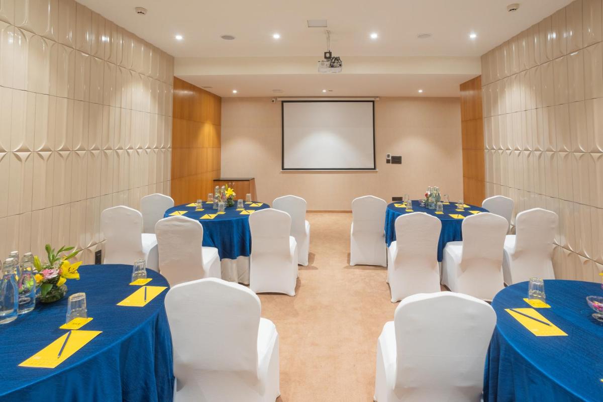 a conference room with tables and chairs and a screen at Golden Tulip Jaipur in Jaipur