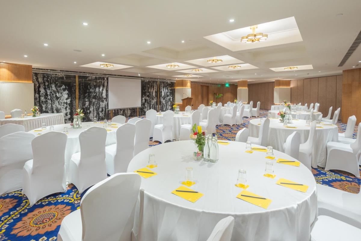a banquet hall with white tables and white chairs at Golden Tulip Jaipur in Jaipur