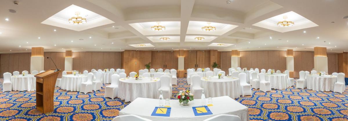 a banquet hall with white tables and chairs and a podium at Golden Tulip Jaipur in Jaipur
