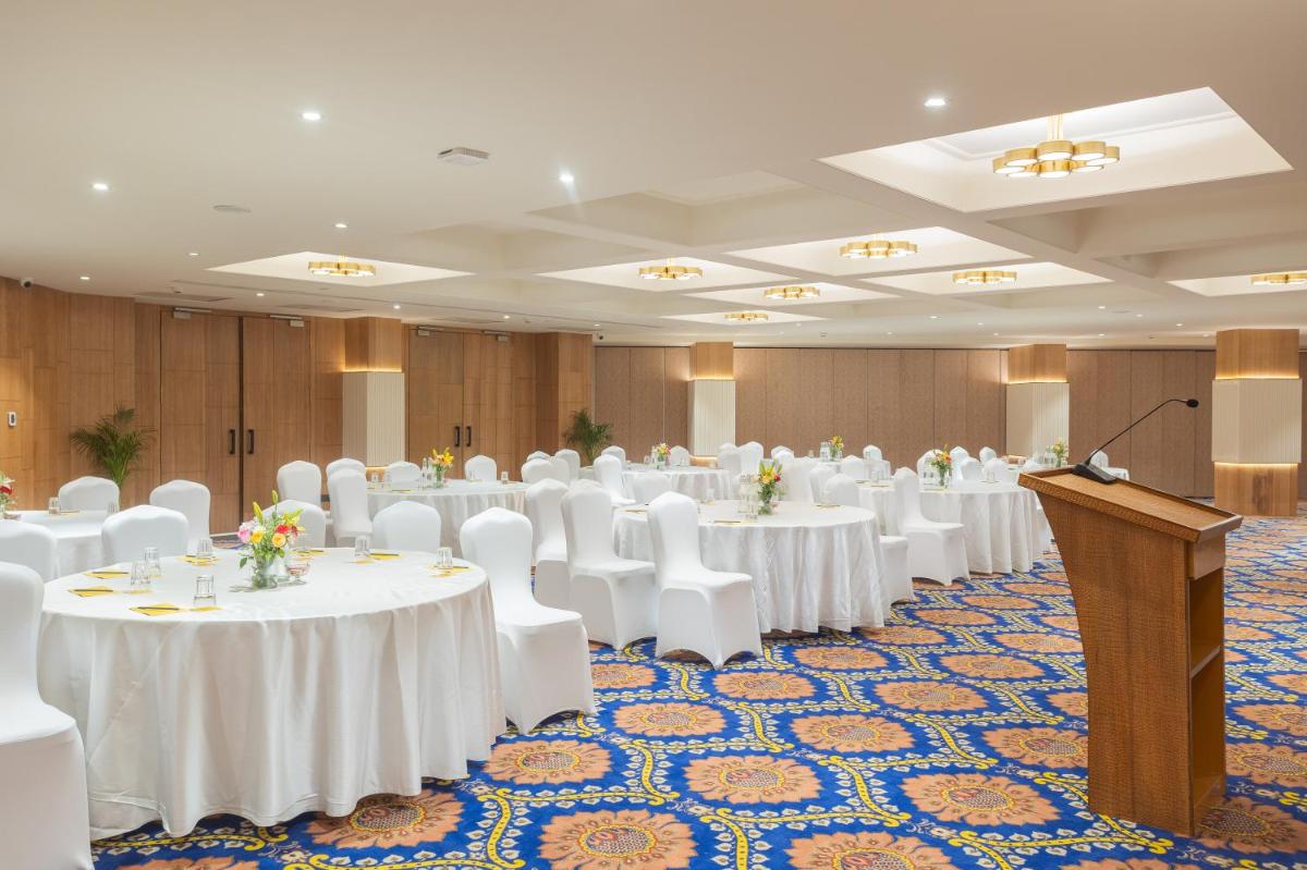 a conference room with white tables and chairs and a podium at Golden Tulip Jaipur in Jaipur