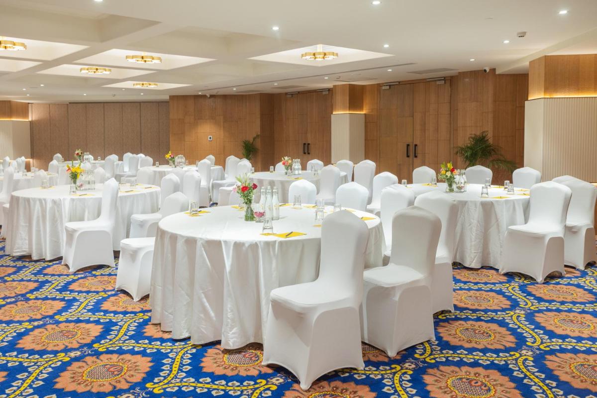 a banquet hall with white tables and white chairs at Golden Tulip Jaipur in Jaipur