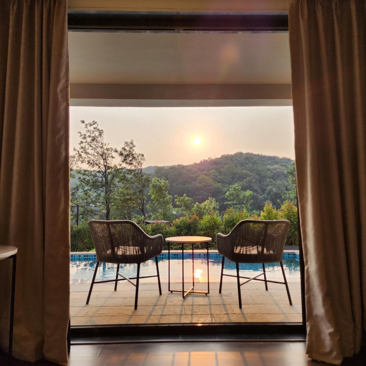 a balcony with a table and two chairs and a view at Courtyard by Marriott Mahabaleshwar in Mahabaleshwar