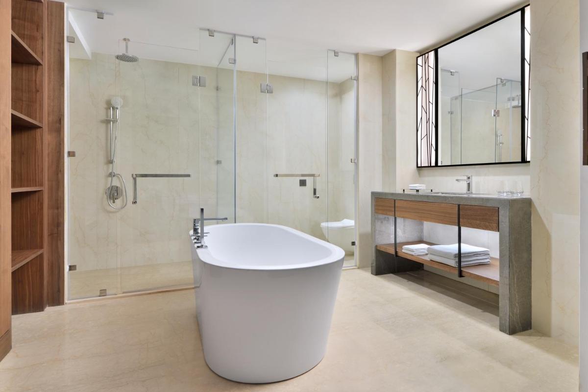 a bathroom with a white tub and a shower at Courtyard by Marriott Mahabaleshwar in Mahabaleshwar