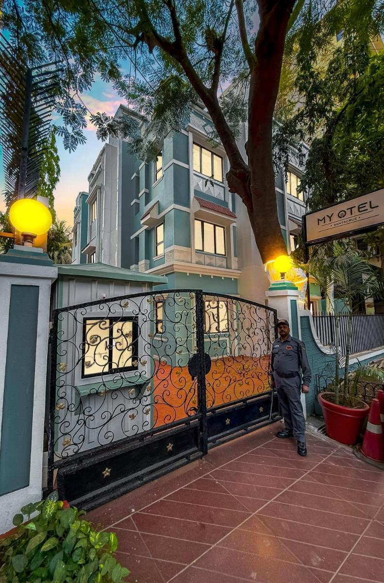 a man standing next to a fence in front of a building at MyOtel - Santacruz in Mumbai