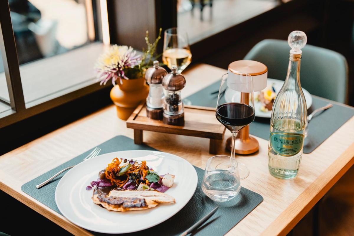 einen Tisch mit einem Teller Essen und einer Flasche Wein in der Unterkunft Hotel Kö59 Düsseldorf - Member of Hommage Luxury Hotels Collection in Düsseldorf