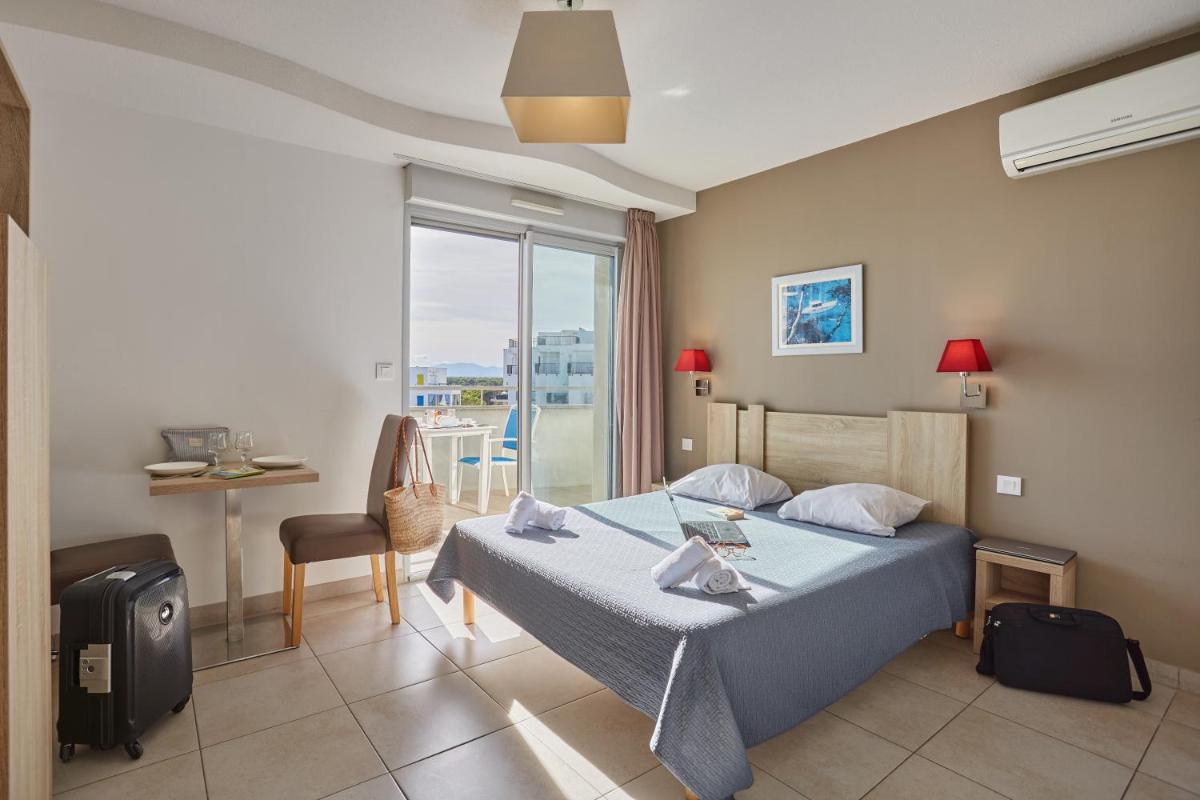 une chambre d'hôtel avec un lit et un balcon dans l'établissement Résidence Odalys Le Lotus Blanc, au Barcarès