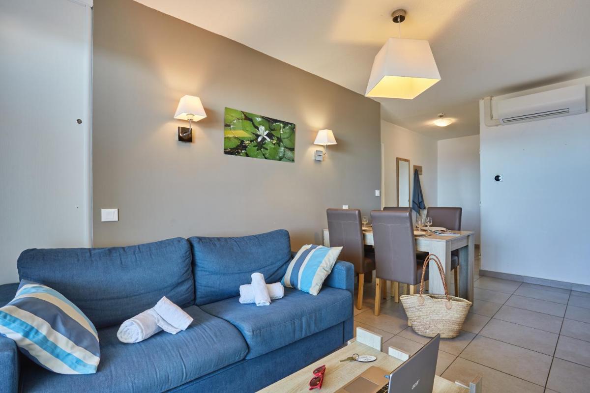 un salon avec un canapé bleu et une table dans l'établissement Résidence Odalys Le Lotus Blanc, au Barcarès