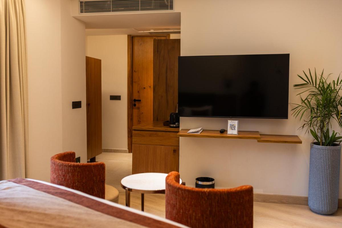 a hotel room with a flat screen tv and chairs at Antalya By Divine Ganga Cottage in Rishīkesh