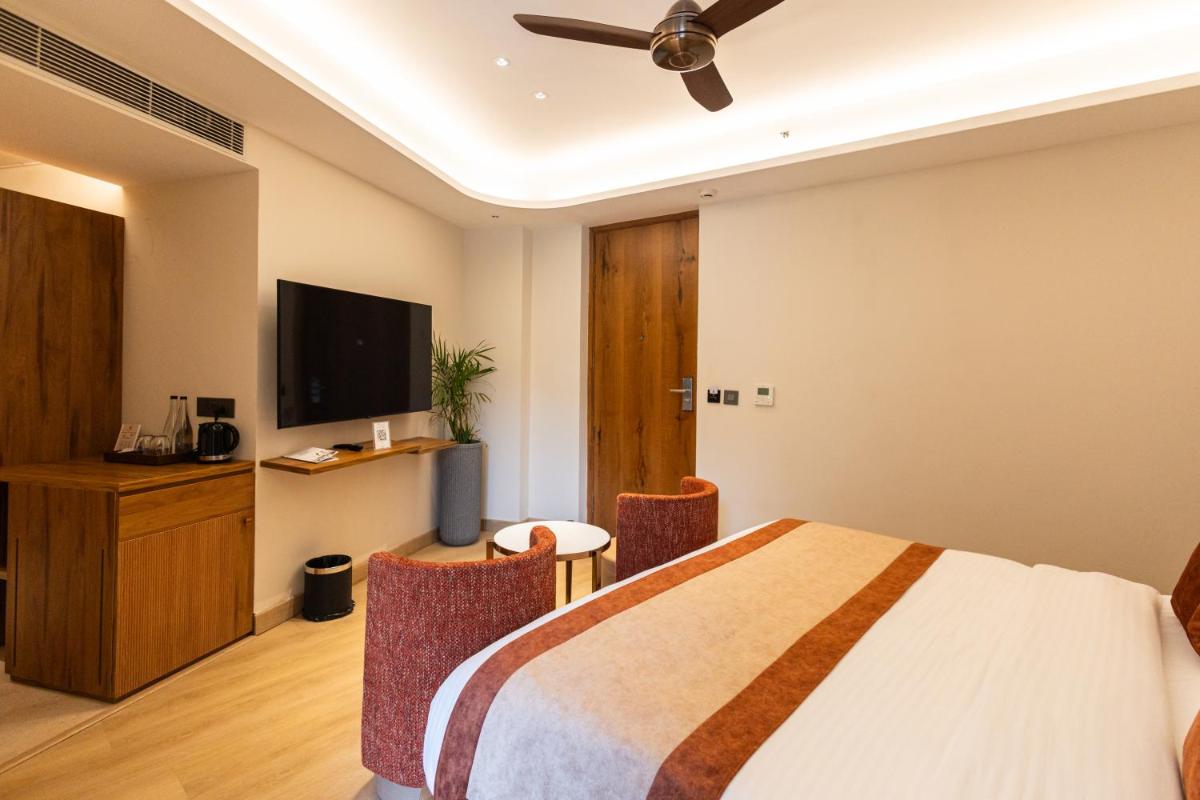 a bedroom with a bed and a flat screen tv at Antalya By Divine Ganga Cottage in Rishīkesh