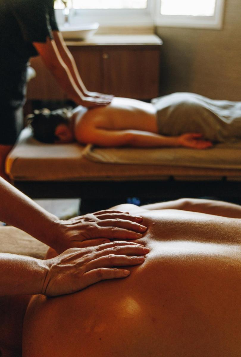 deux femmes allongées sur des lits avec leurs mains sur un corps dans l'établissement Hotel Corsica & Spa Serena, à Calvi