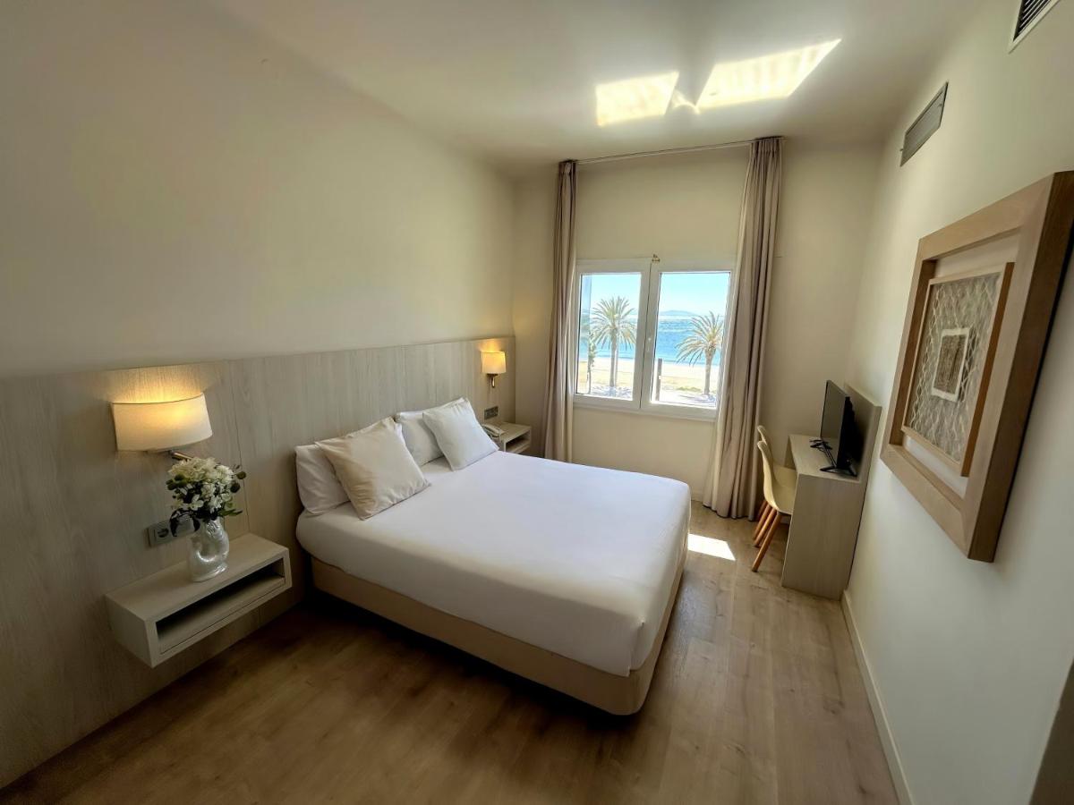 Un dormitorio con una gran cama blanca y una ventana. en Hotel Marina, en Roses