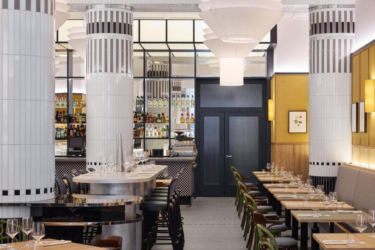 ein Restaurant mit Tischen und Stühlen und einer Bar in der Unterkunft Kimpton Main Frankfurt by IHG in Frankfurt am Main