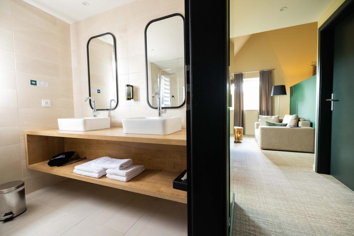 une salle de bains avec deux lavabos et un miroir dans l'établissement Logis Hôtel Restaurant & Spa La Rochette, à Labaroche