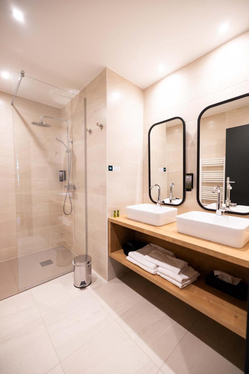 une salle de bains avec deux lavabos et une douche dans l'établissement Logis Hôtel Restaurant & Spa La Rochette, à Labaroche 34 autres photos