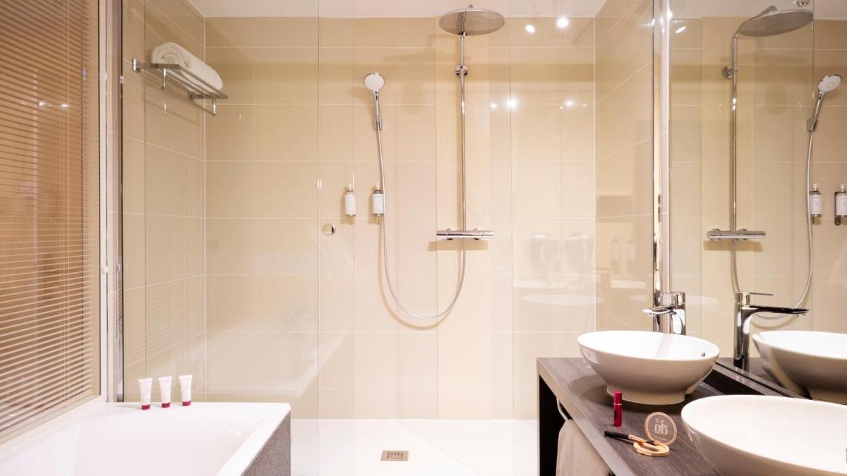 une salle de bains avec douche, deux lavabos et baignoire dans l'établissement Residhome Suites Paris Sénart, à Lieusaint
