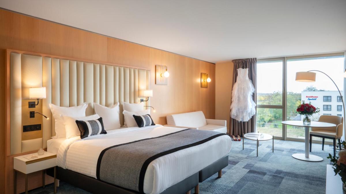 une chambre d'hôtel avec un grand lit et une fenêtre dans l'établissement Residhome Suites Paris Sénart, à Lieusaint