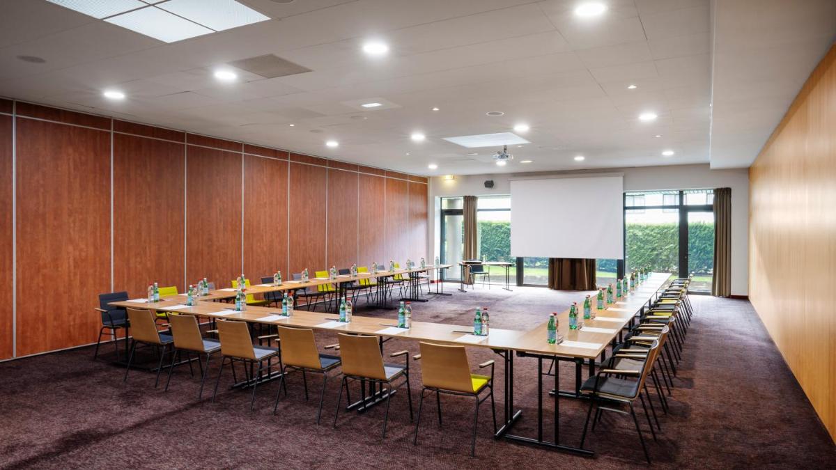 une grande salle de conférence avec une longue table et des chaises dans l'établissement Residhome Suites Paris Sénart, à Lieusaint 35 autres photos