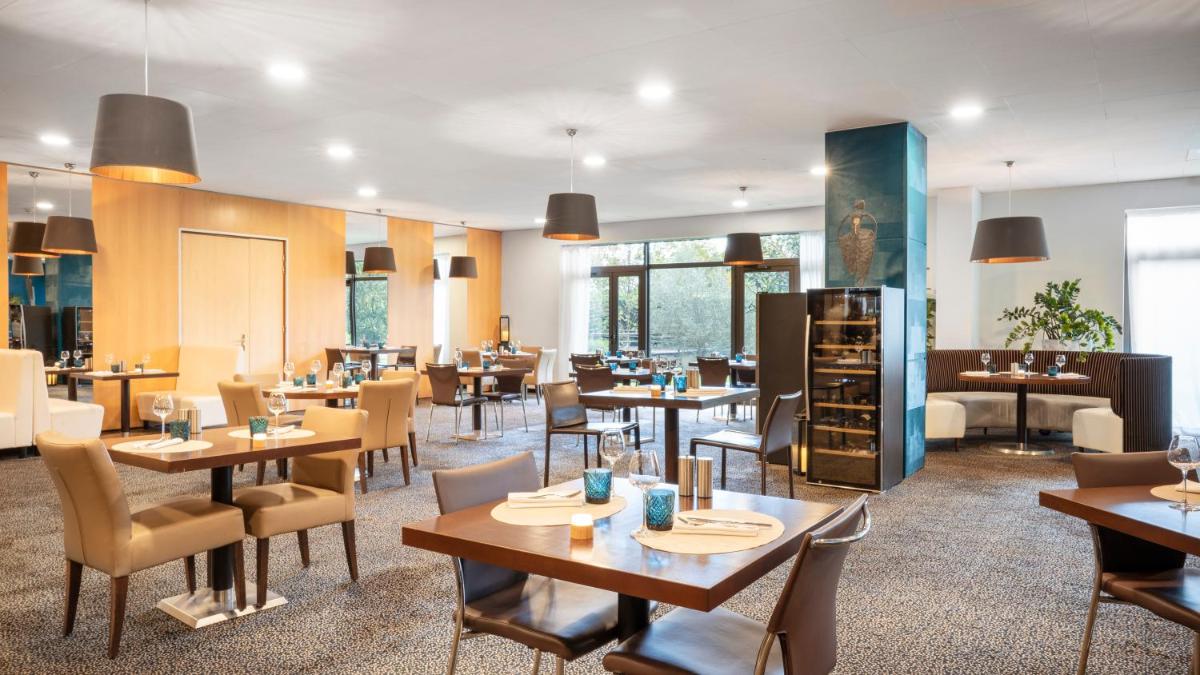 un restaurant avec des tables et des chaises en bois et des tables et des chaises dans l'établissement Residhome Suites Paris Sénart, à Lieusaint