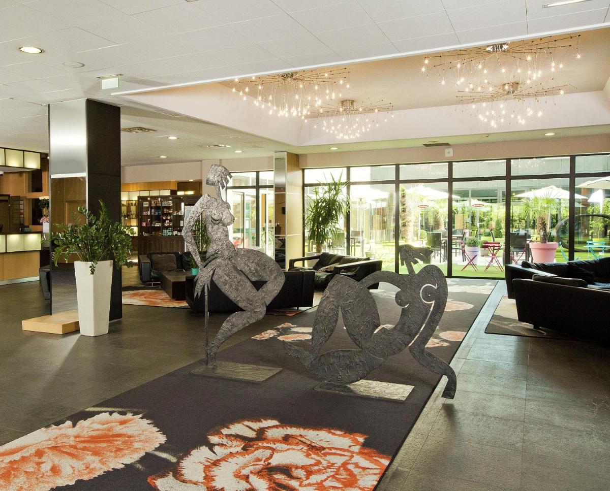 un hall avec une sculpture d'une personne assise sur un banc dans l'établissement Residhome Suites Paris Sénart, à Lieusaint