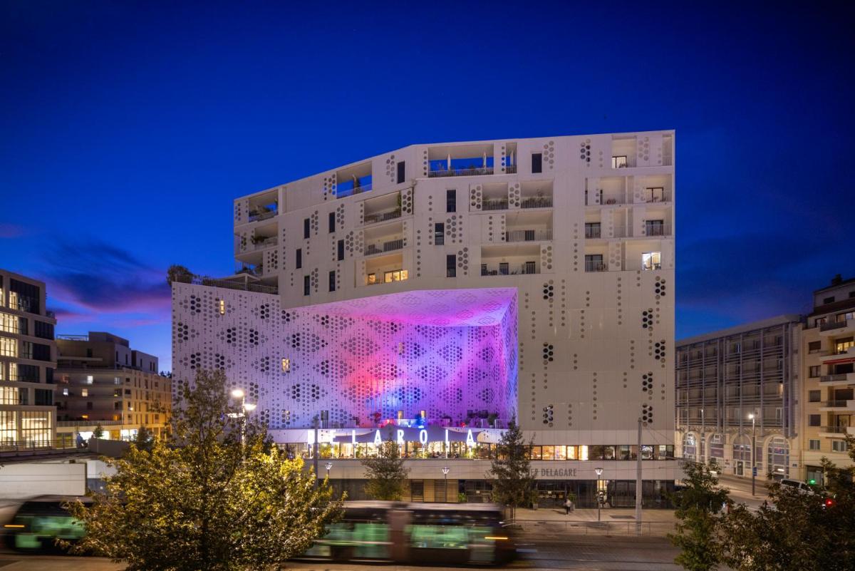 un grand bâtiment avec une façade colorée la nuit dans l'établissement Belaroïa Montpellier Centre Saint Roch, à Montpellier