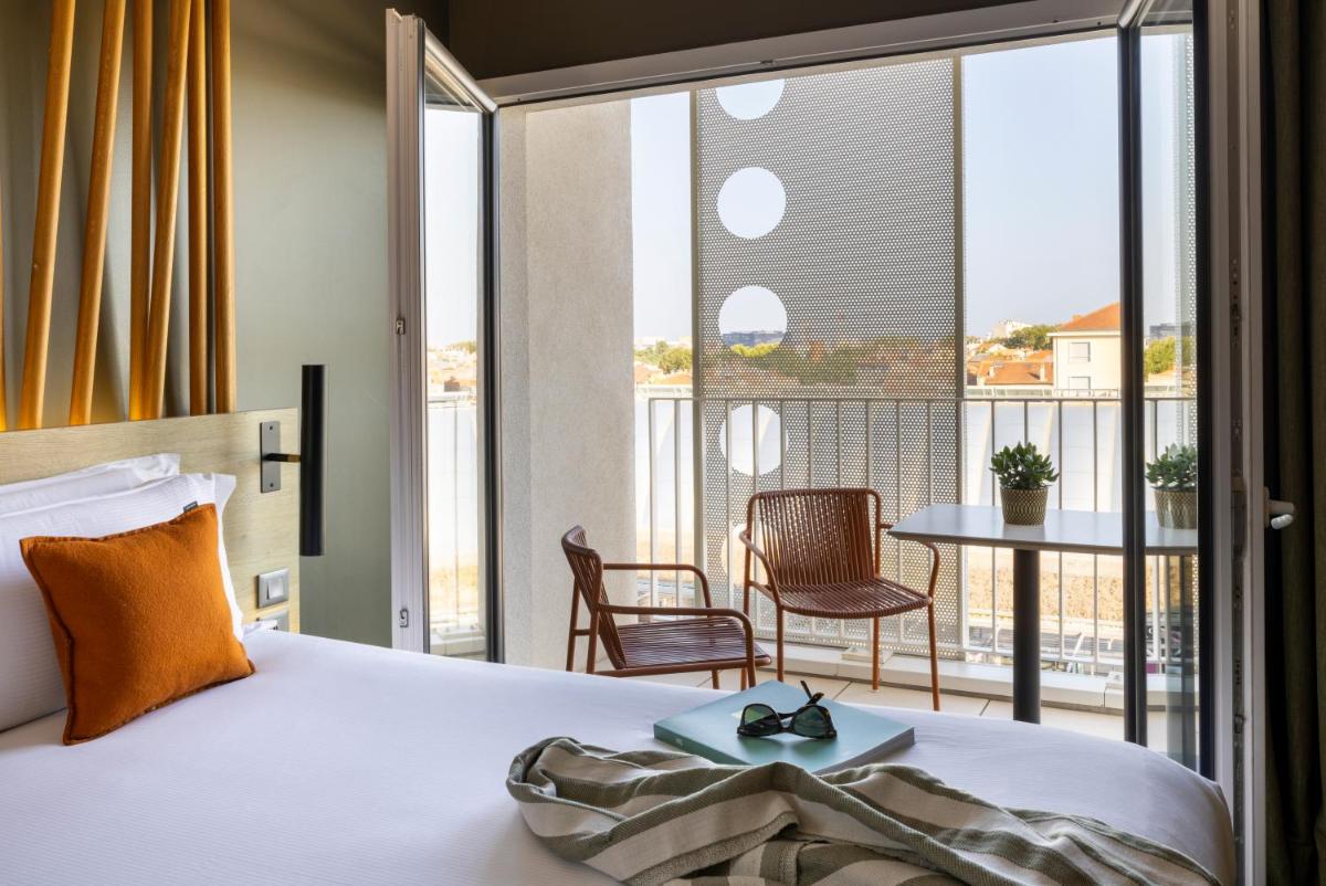 une chambre avec un lit et un balcon avec une table dans l'établissement Belaroïa Montpellier Centre Saint Roch, à Montpellier