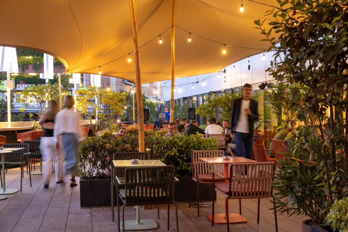 un restaurant avec des tables et des chaises et des personnes se promenant dans les environs dans l'établissement Hotel Campanile Montpellier Centre St Roch, à Montpellier