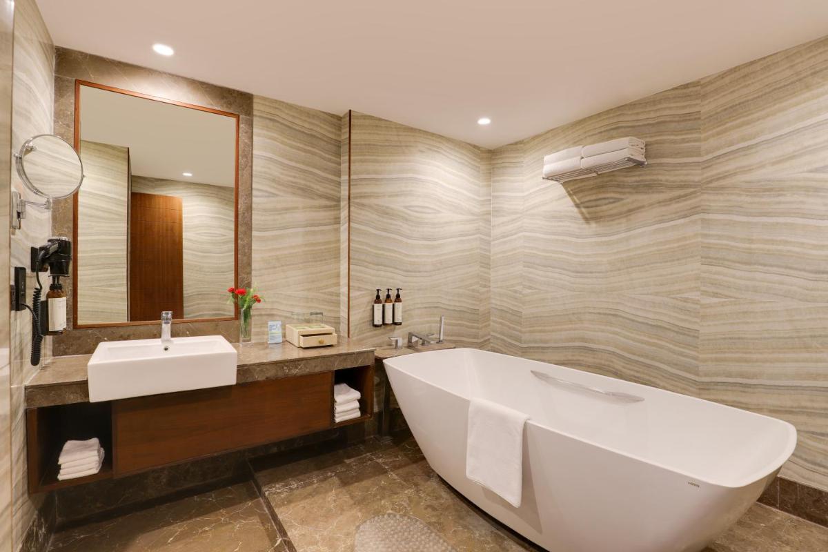 a bathroom with a tub and a sink and a mirror at Saura Hotel, Agra - A Club Mahindra Associate in Agra