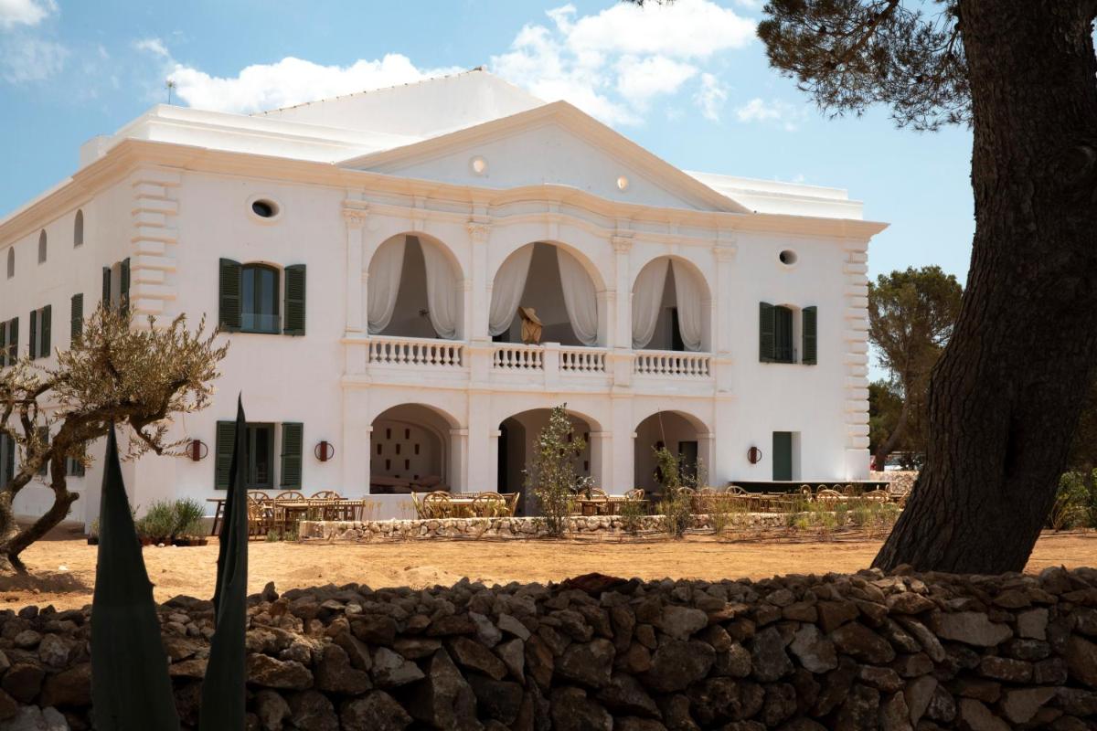 Un gran edificio blanco con un árbol delante. en Menorca Experimental, en Alaior