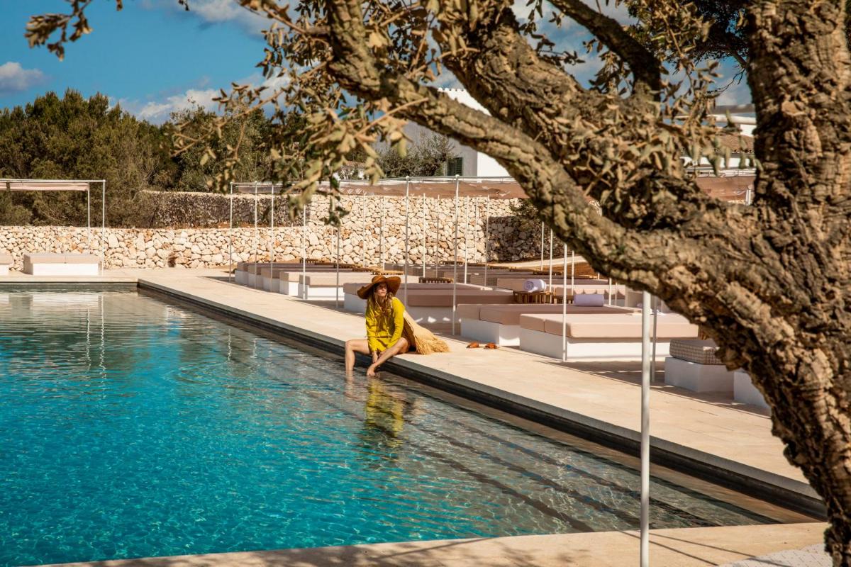 una mujer sentada en el agua junto a una piscina en Menorca Experimental, en Alaior