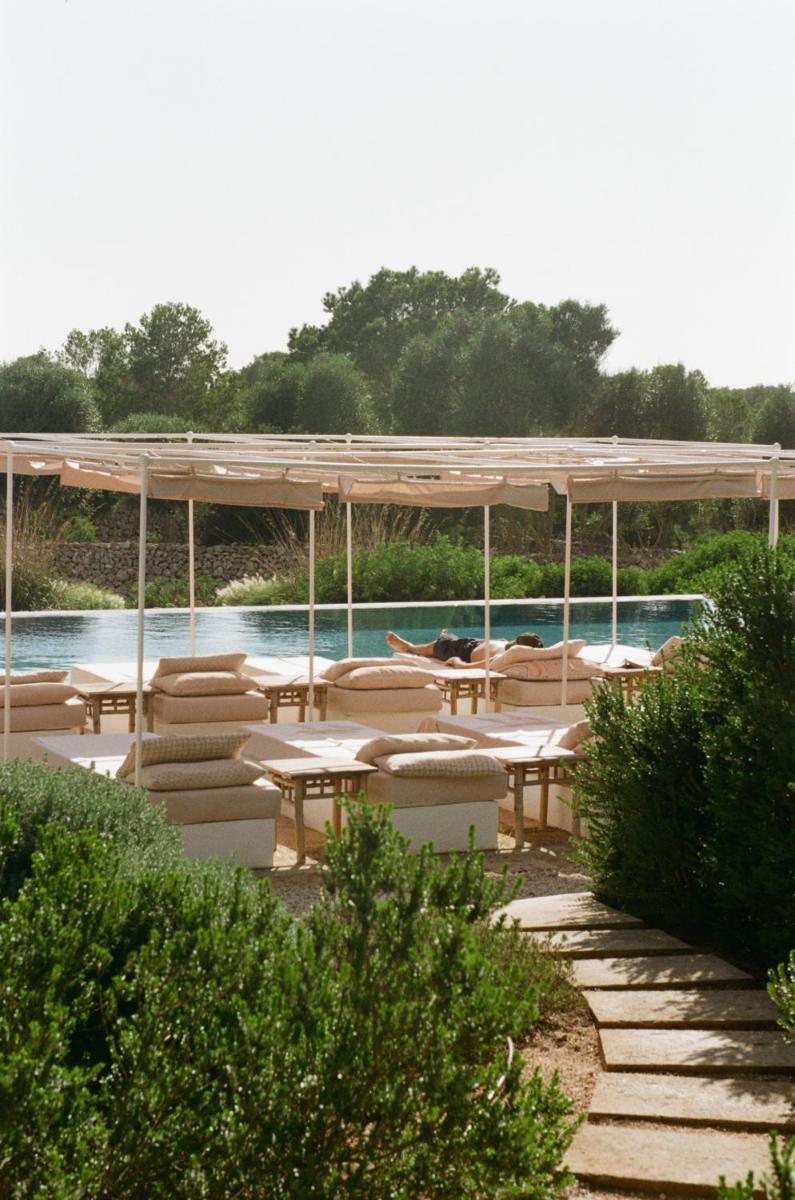 Un patio con mesas y sillas y una piscina. en Menorca Experimental, en Alaior
