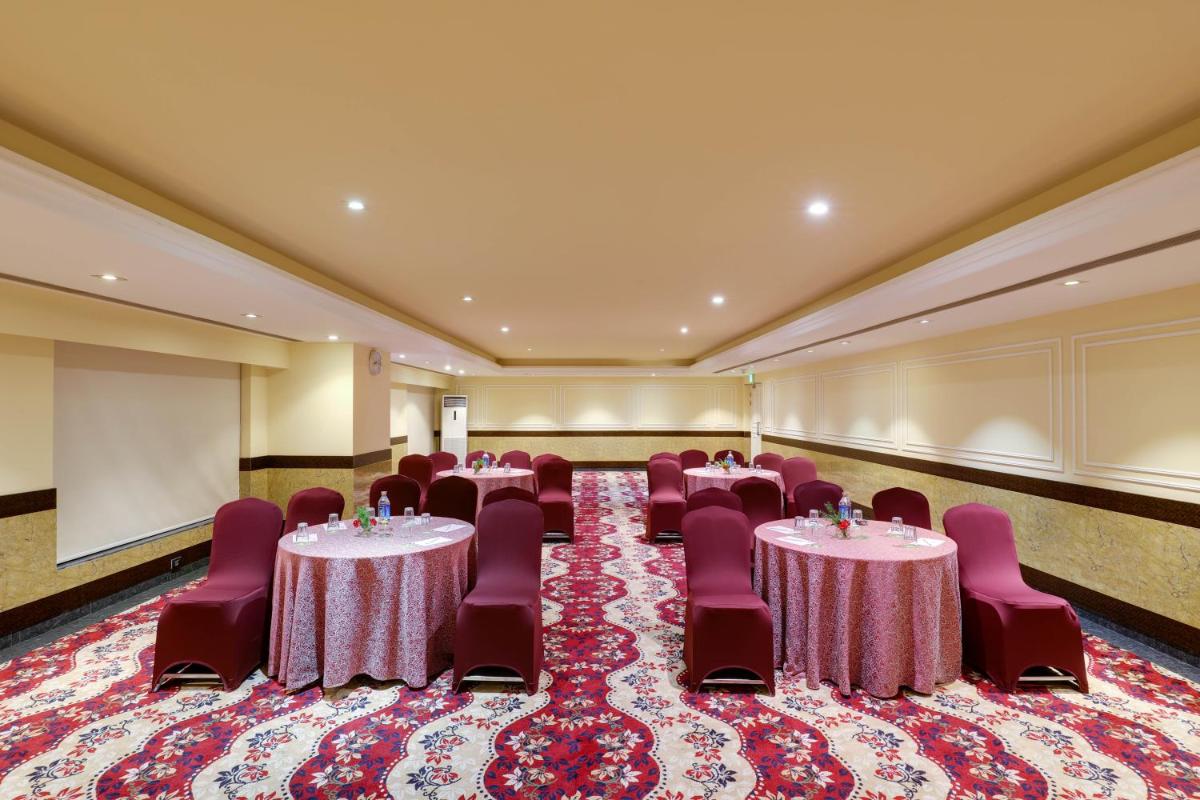 a banquet hall with tables and chairs and a stage at Saura Hotel, Agra - A Club Mahindra Associate in Agra