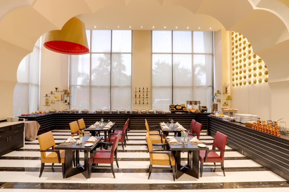 a dining room with tables and chairs and windows at Saura Hotel, Agra - A Club Mahindra Associate in Agra