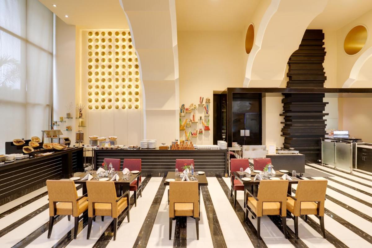 a restaurant with tables and chairs and a buffet at Saura Hotel, Agra - A Club Mahindra Associate in Agra
