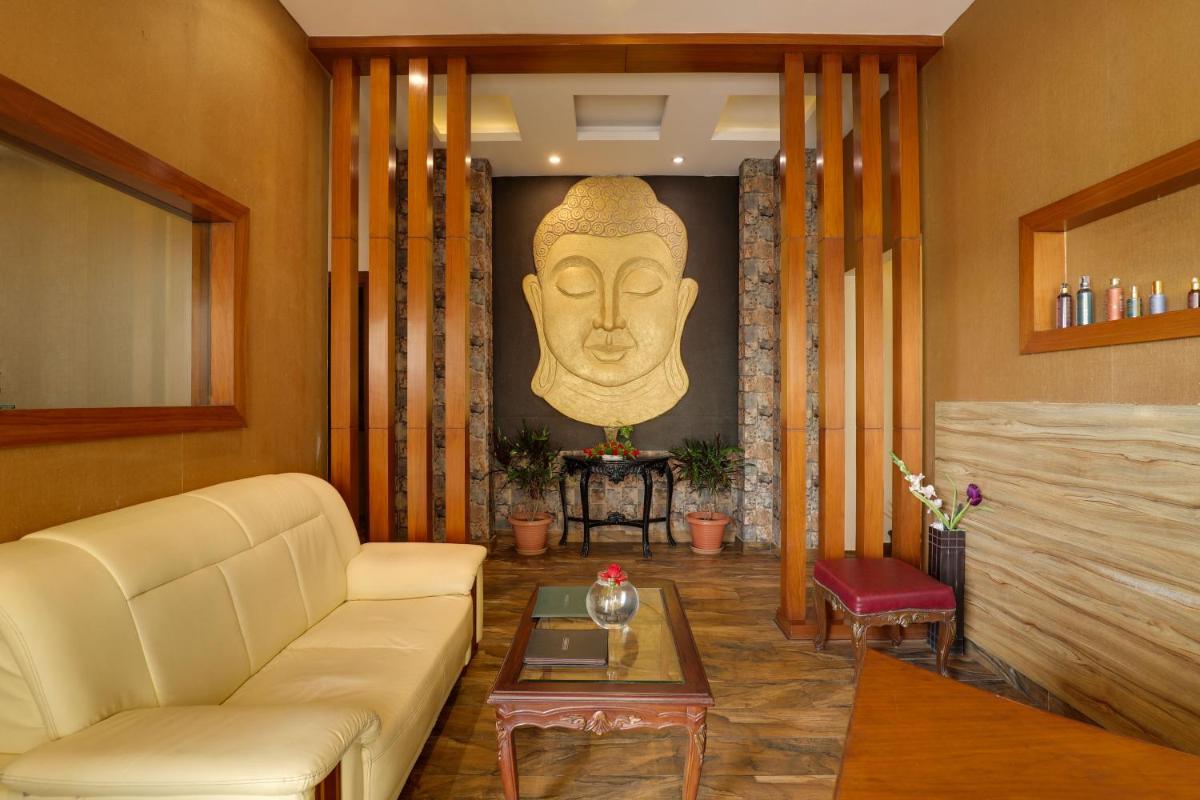 a living room with a couch and a giant head on the wall at Saura Hotel, Agra - A Club Mahindra Associate in Agra
