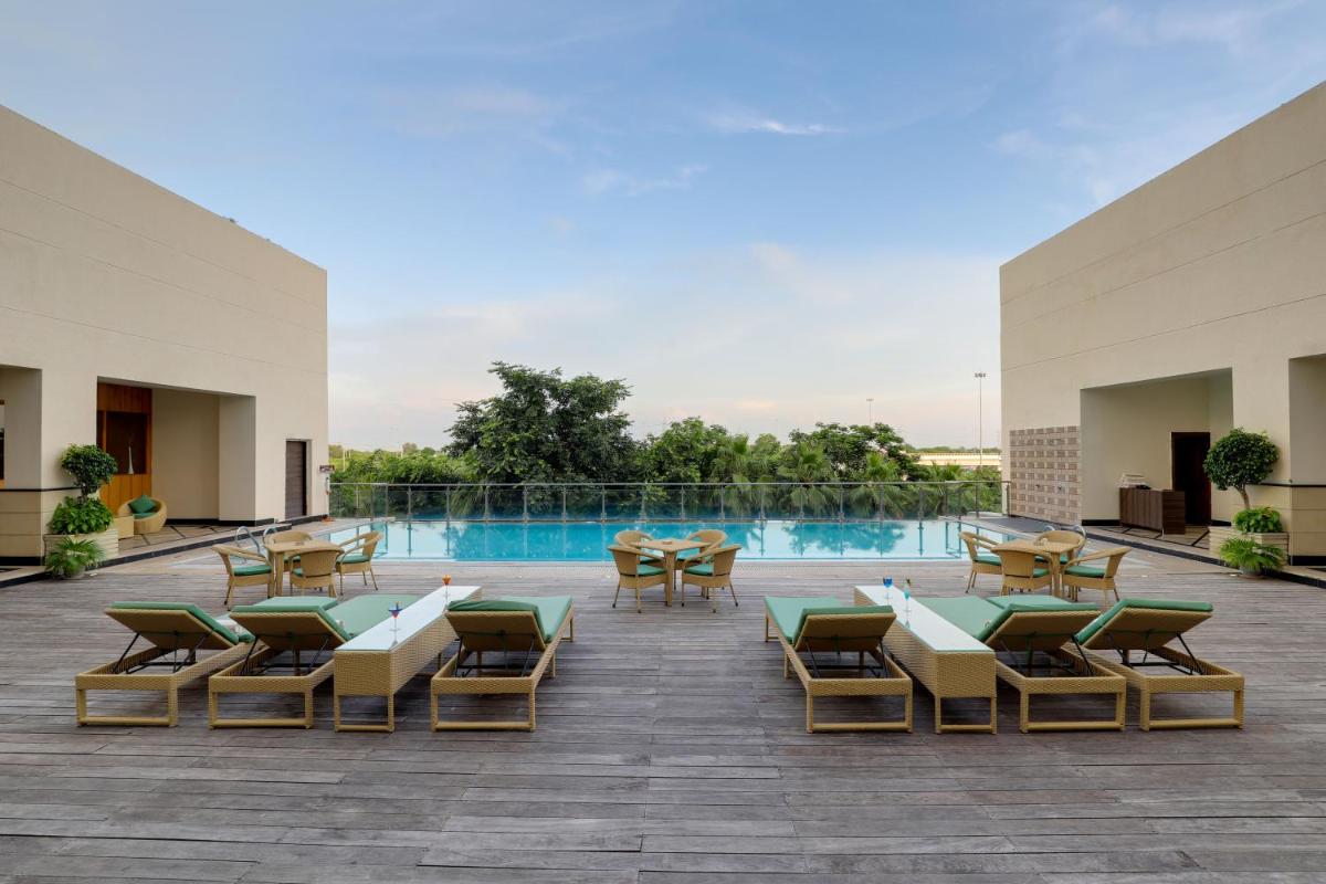a patio with chairs and tables and a swimming pool at Saura Hotel, Agra - A Club Mahindra Associate in Agra
