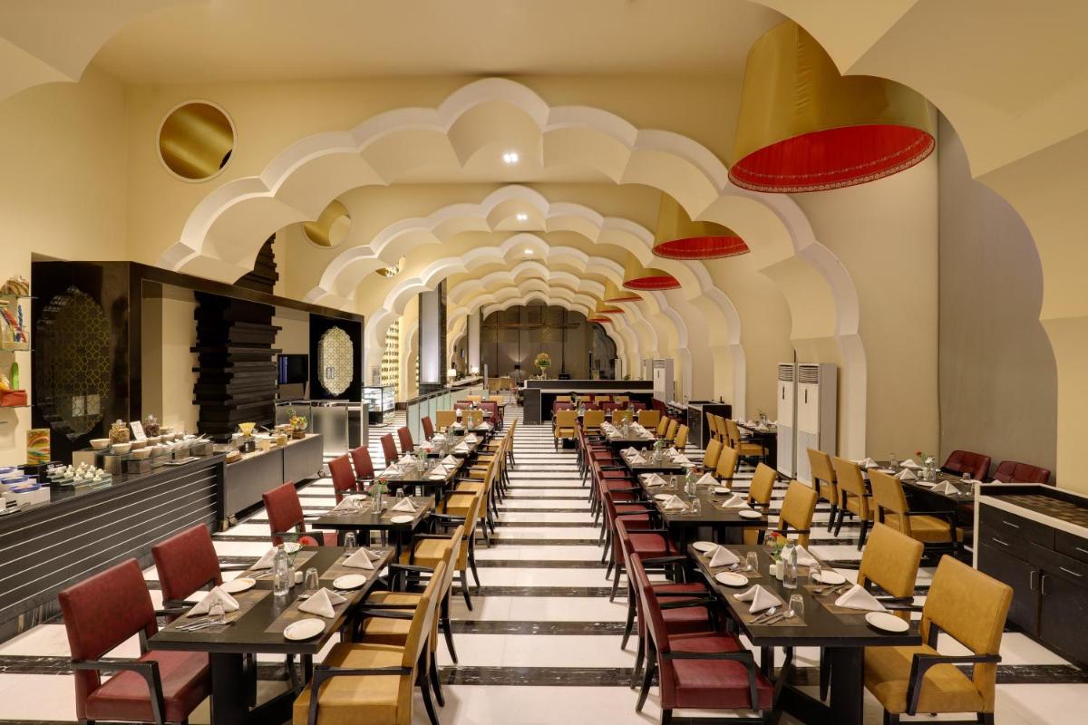 a long dining room with tables and chairs at Saura Hotel, Agra - A Club Mahindra Associate in Agra