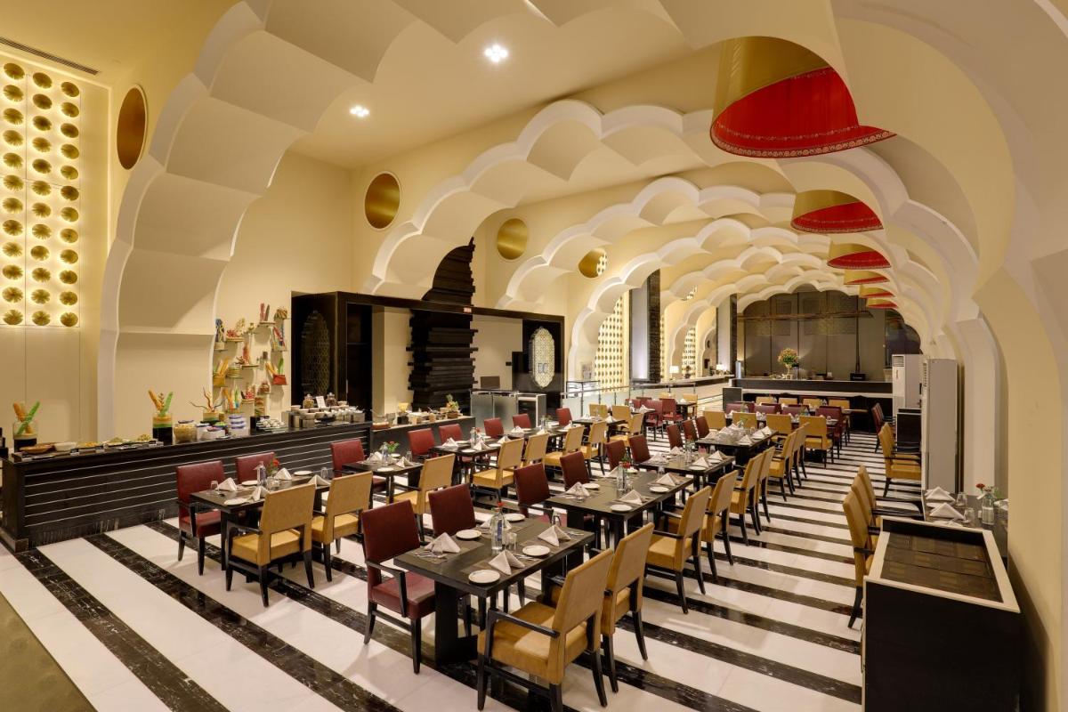 a restaurant with tables and chairs in a building at Saura Hotel, Agra - A Club Mahindra Associate in Agra