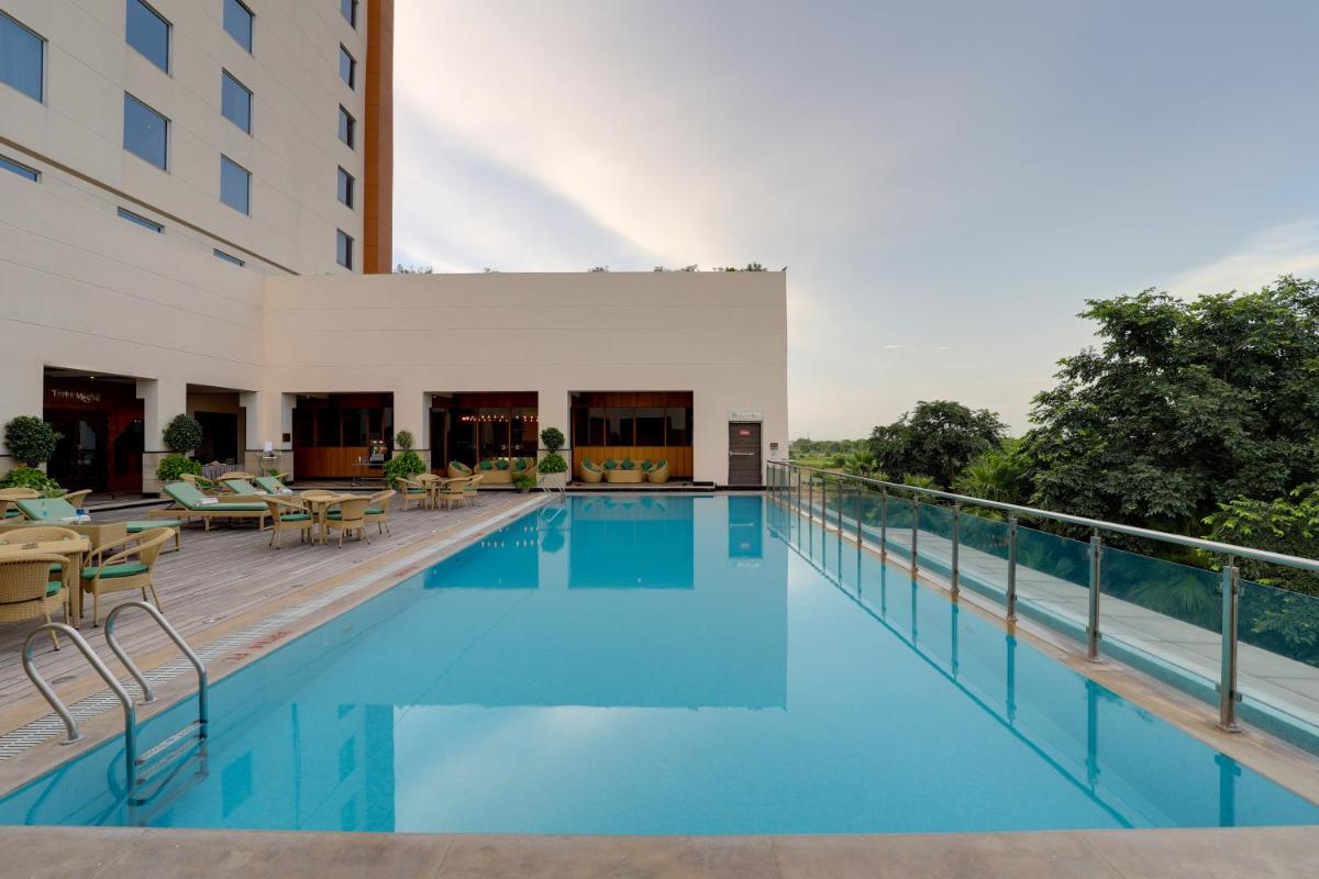 a view of the pool at a hotel with tables and chairs at Saura Hotel, Agra - A Club Mahindra Associate in Agra