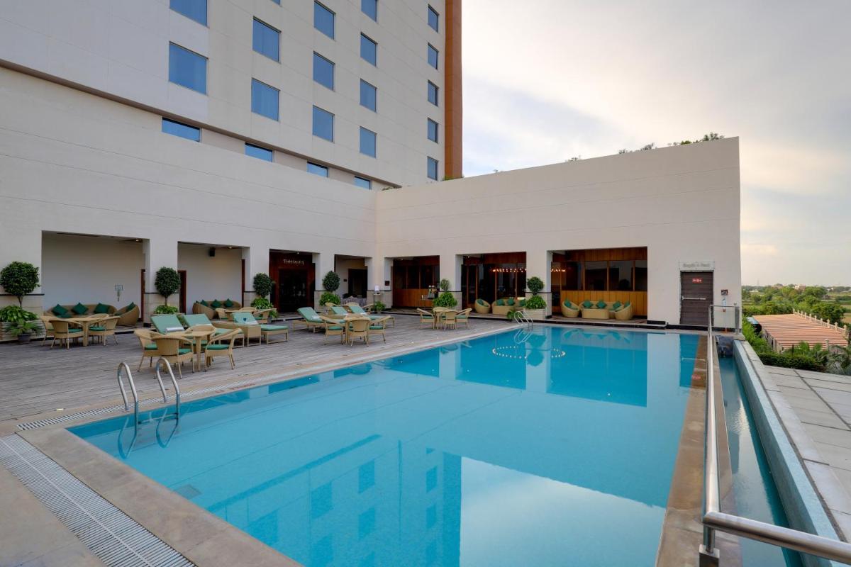 a pool at a hotel with tables and chairs at Saura Hotel, Agra - A Club Mahindra Associate in Agra