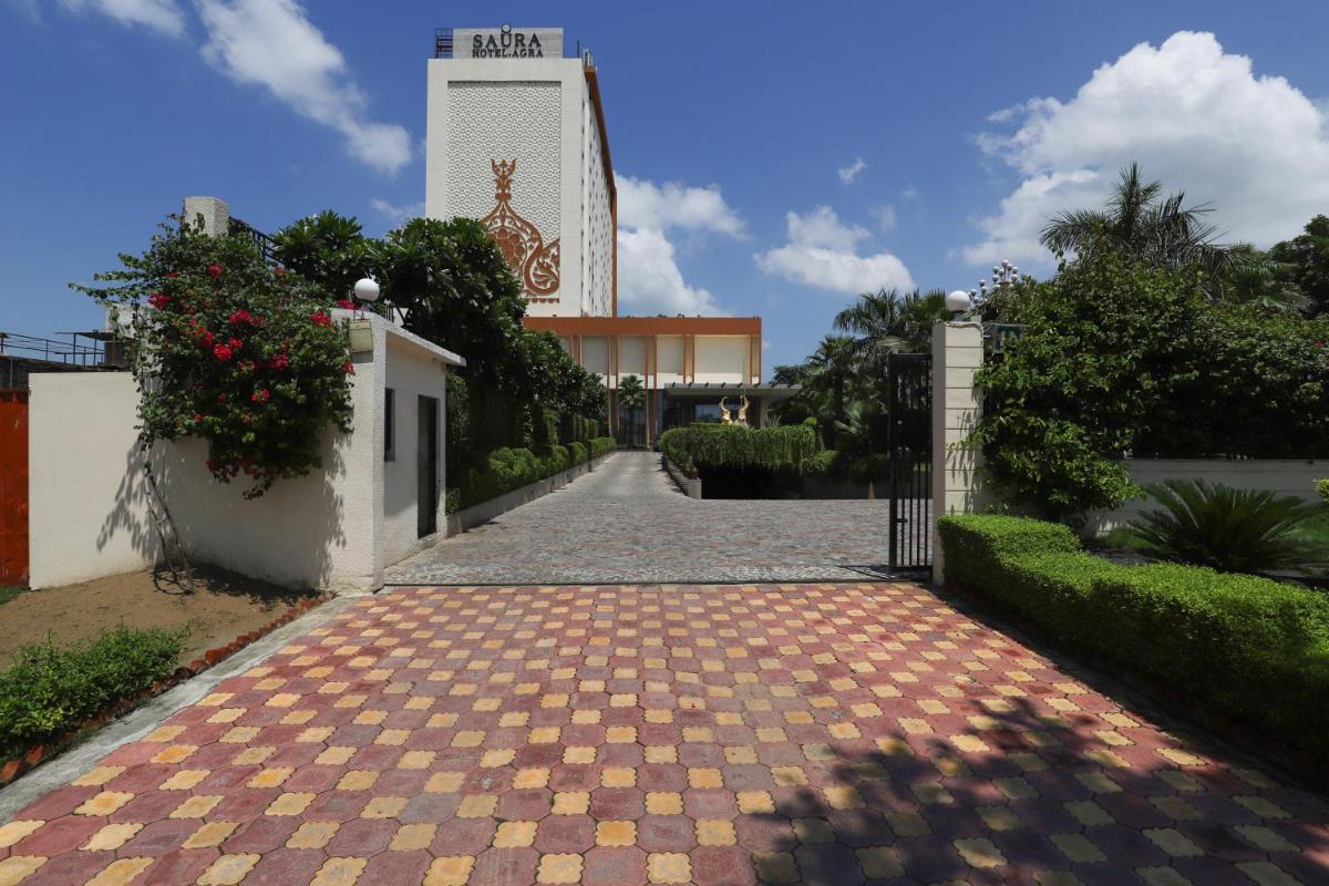 a driveway leading to a building with a clock tower at Saura Hotel, Agra - A Club Mahindra Associate in Agra