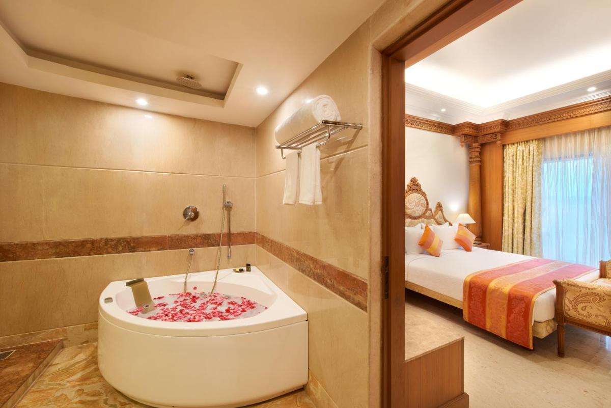 a bathroom with a tub and a bedroom with a bed at Accord Puducherry in Puducherry