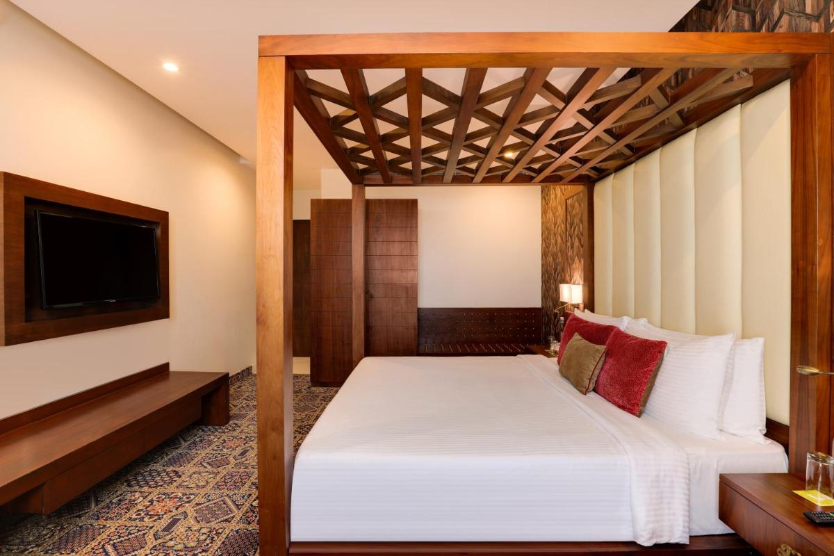 a bedroom with a bed and a flat screen tv at Saura Hotel, Agra - A Club Mahindra Associate in Agra