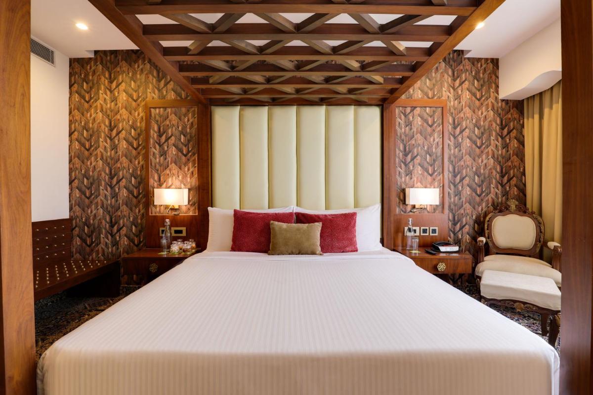 a bedroom with a large bed with red pillows at Saura Hotel, Agra - A Club Mahindra Associate in Agra