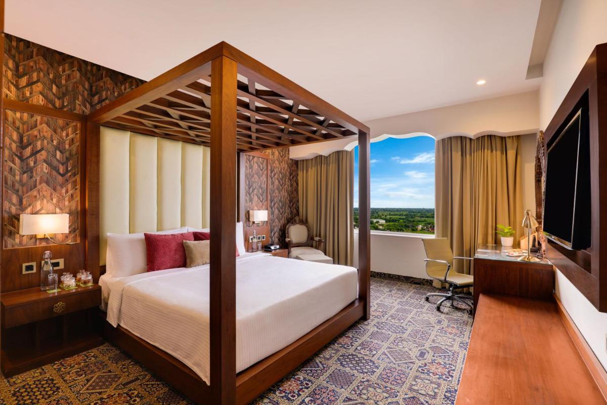 a hotel room with a bed and a large window at Saura Hotel, Agra - A Club Mahindra Associate in Agra