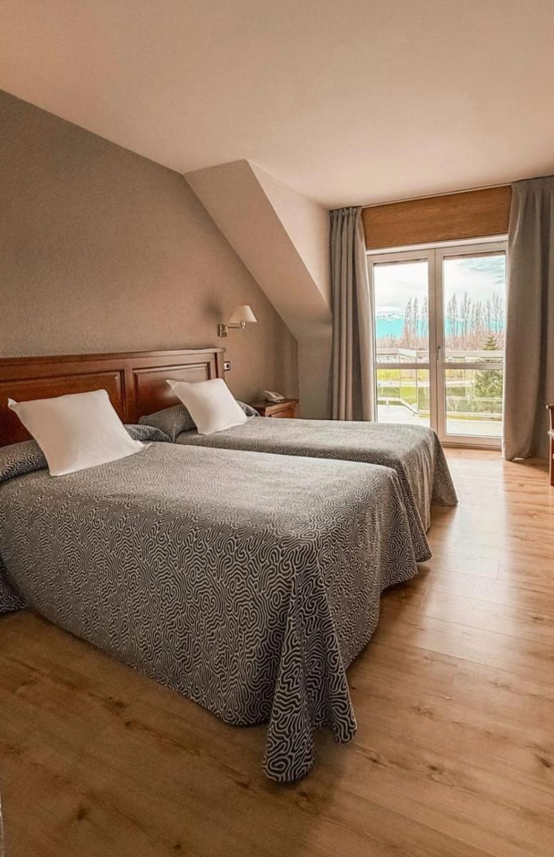 Un dormitorio con dos camas y una gran ventana. en Puigcerda Park Hotel, en Puigcerdà