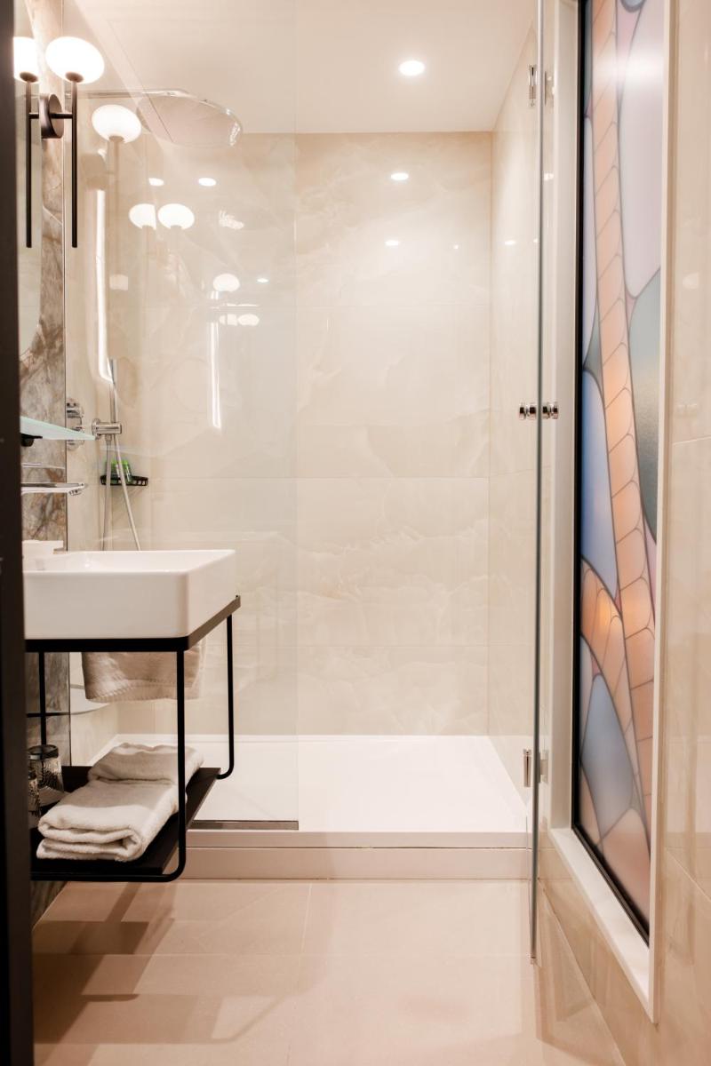 une salle de bain avec lavabo et douche dans l'établissement Grand Hotel Saint Michel, à Paris