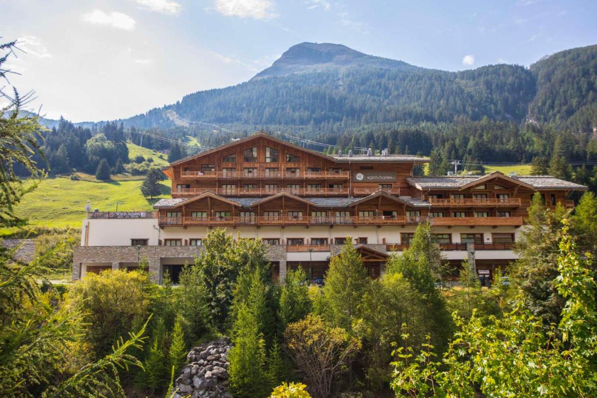 un grand bâtiment avec une montagne en arrière-plan dans l'établissement Hôtel Saint Charles Val Cenis, à Lanslebourg-Mont-Cenis