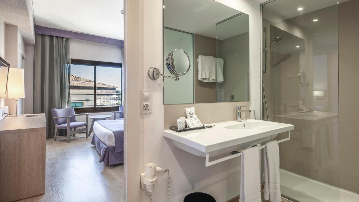 Un baño con lavabo, espejo y cama. en Hotel Be Live Adults Only Marivent, en Palma de Mallorca