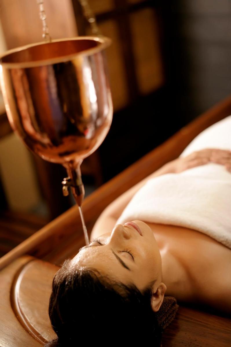 a woman laying in a bed with a glass of wine at Gokulam Grand Hotel & Spa Bangalore in Bengaluru a woman laying in a bed with a glass of wine at Gokulam Grand Hotel & Spa Bangalore in Bengaluru