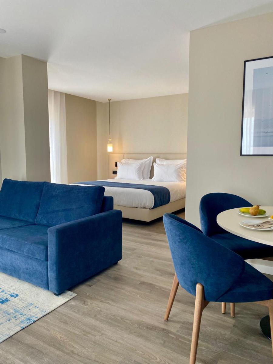 um quarto de hotel com uma cama e um sofá azul em AP Sines - Costa Alentejana em Sines